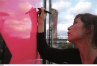 Une femme dessine sur un mur rose